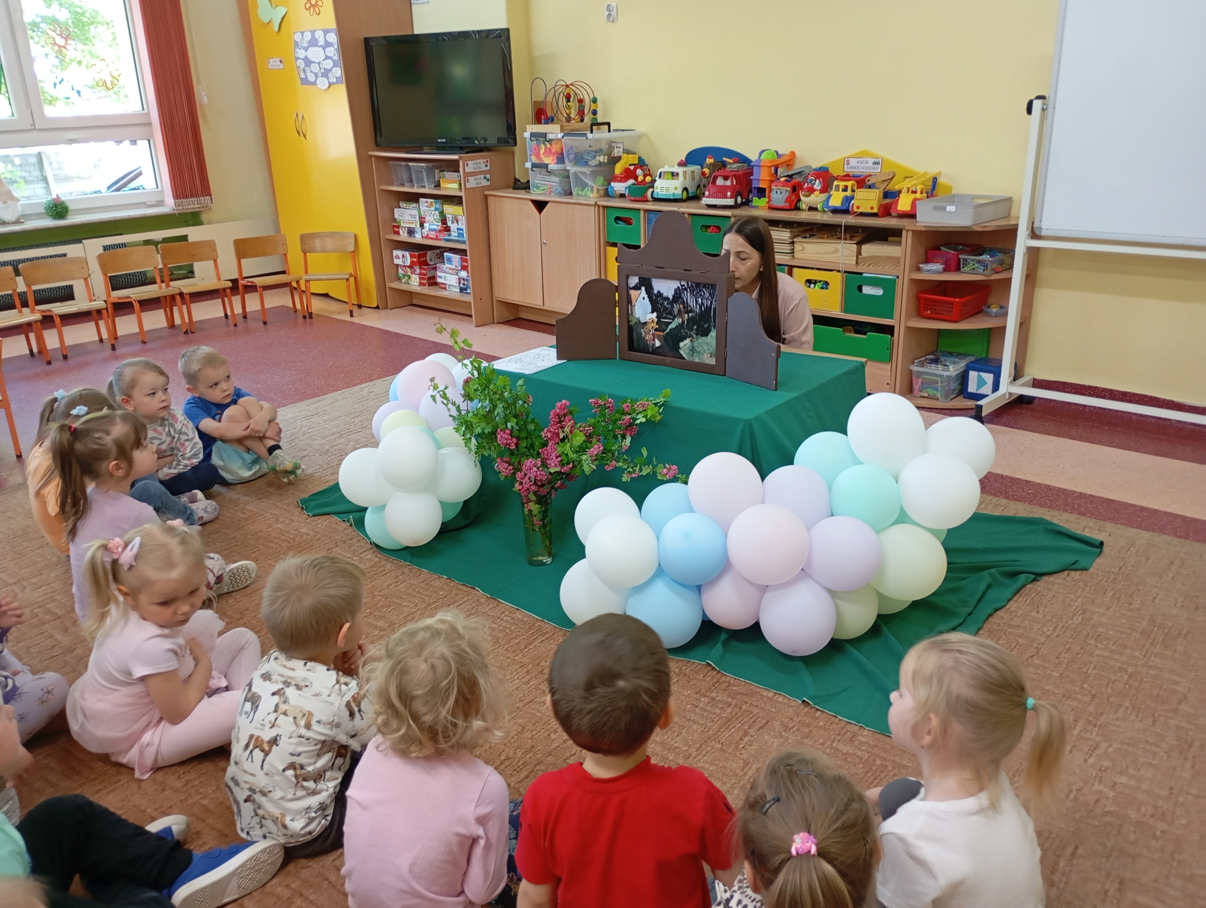 Przedszkolaki oglądają teatrzyk kamishibai.