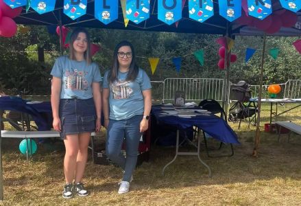 Bibliotekarki pozują przed stoiskiem biblioteki promującym czytelnictwo.